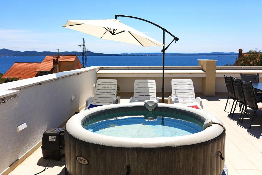 a hot tub on a balcony with chairs and an umbrella at Vidalis, no 1 in Kožino