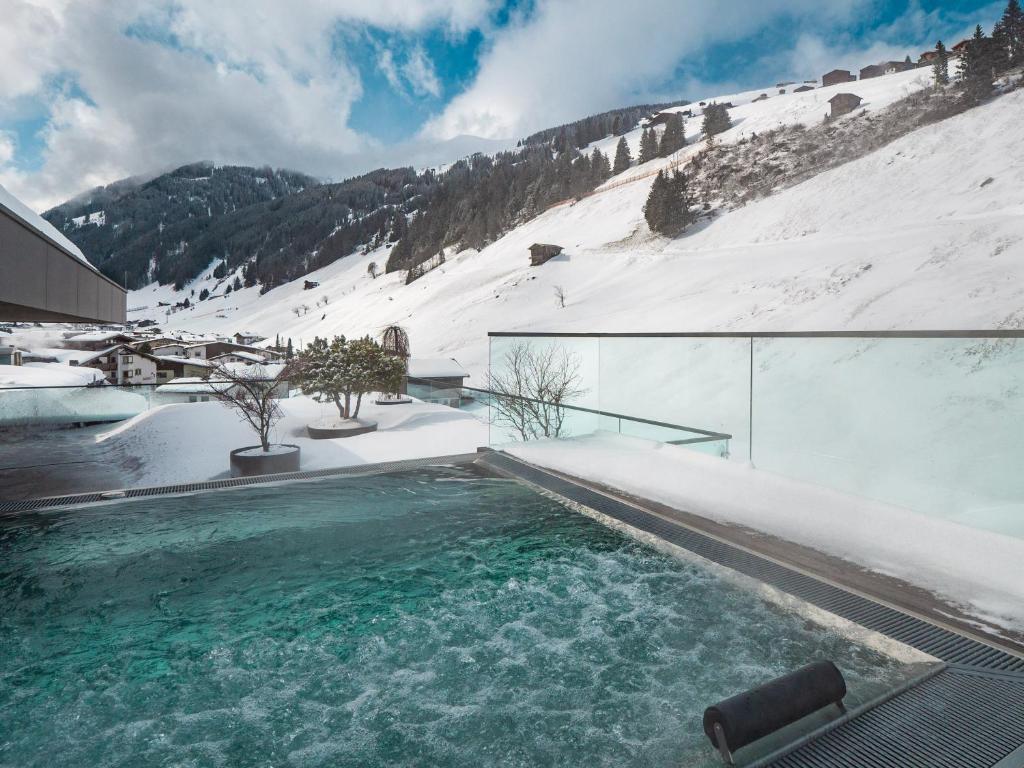 una piscina en la nieve en una casa en Hotel Tirolerhof 4 Sterne Superior, en Tux