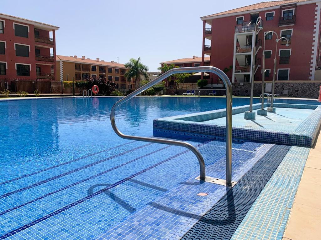 a swimming pool with a handrail in a building at Luminoso y Elegante, piscinas y pistas de pádel in Palm-mar