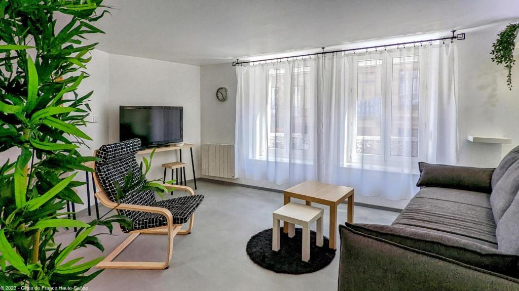 a living room with a couch and chairs and a tv at Suite Fidji in Luxeuil-les-Bains