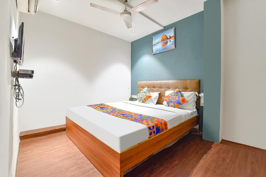 a bedroom with a bed with a blue wall at FabHotel Nidhivan, Udhna Junction in Surat