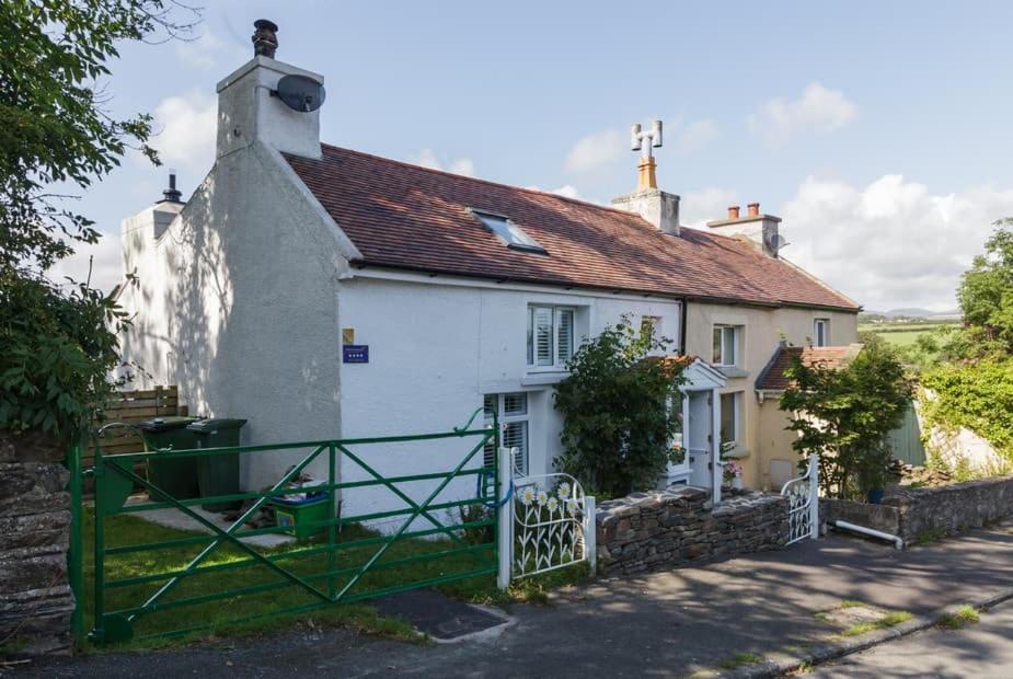 a white house with a green gate in front of it at Rivendell Cottage in Douglas