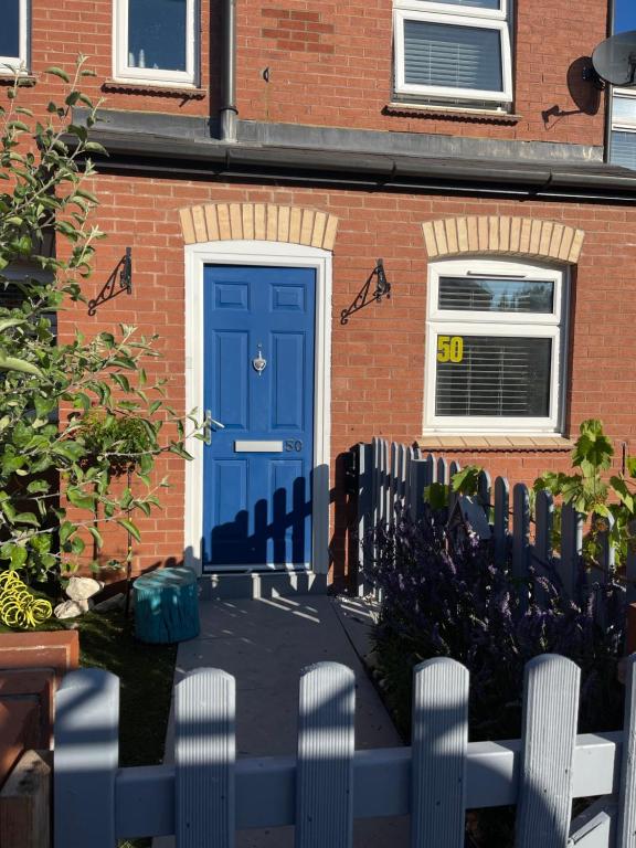 uma porta azul numa casa de tijolos com uma cerca em Room in family home em Teversham