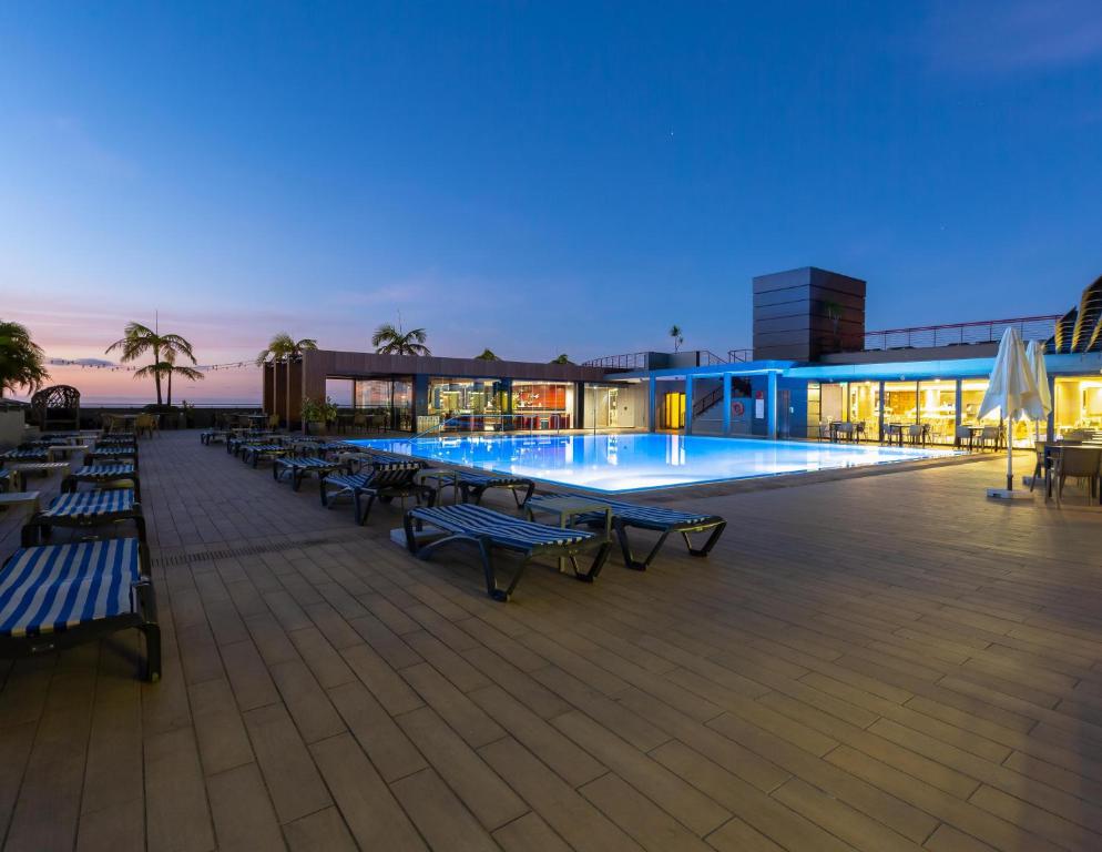 - un bâtiment doté d'une piscine avec des tables et des bancs dans l'établissement The Views Monumental, à Funchal