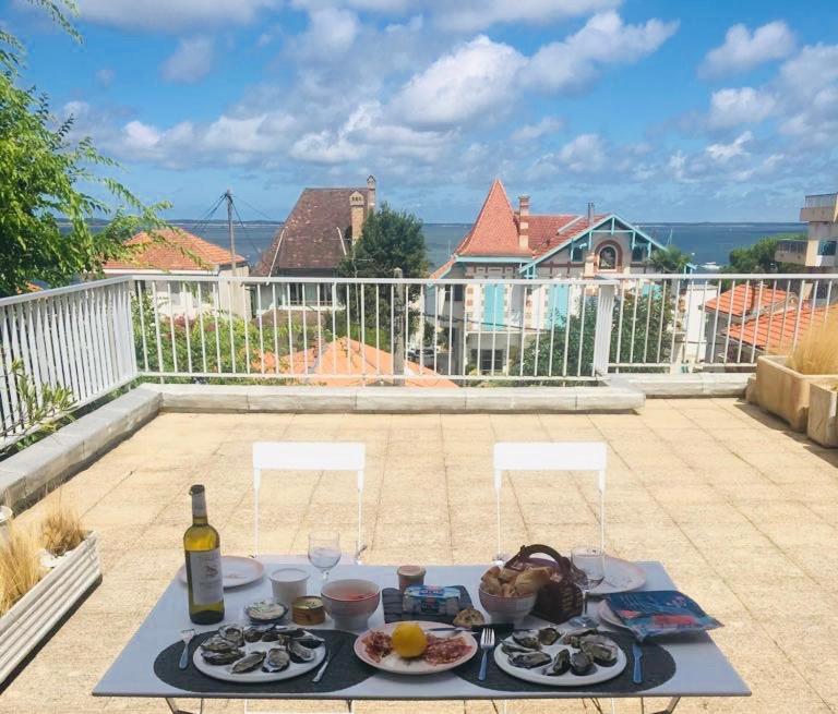 a table with plates of food and a bottle of wine at La Rose des Sables Arcachon in Arcachon