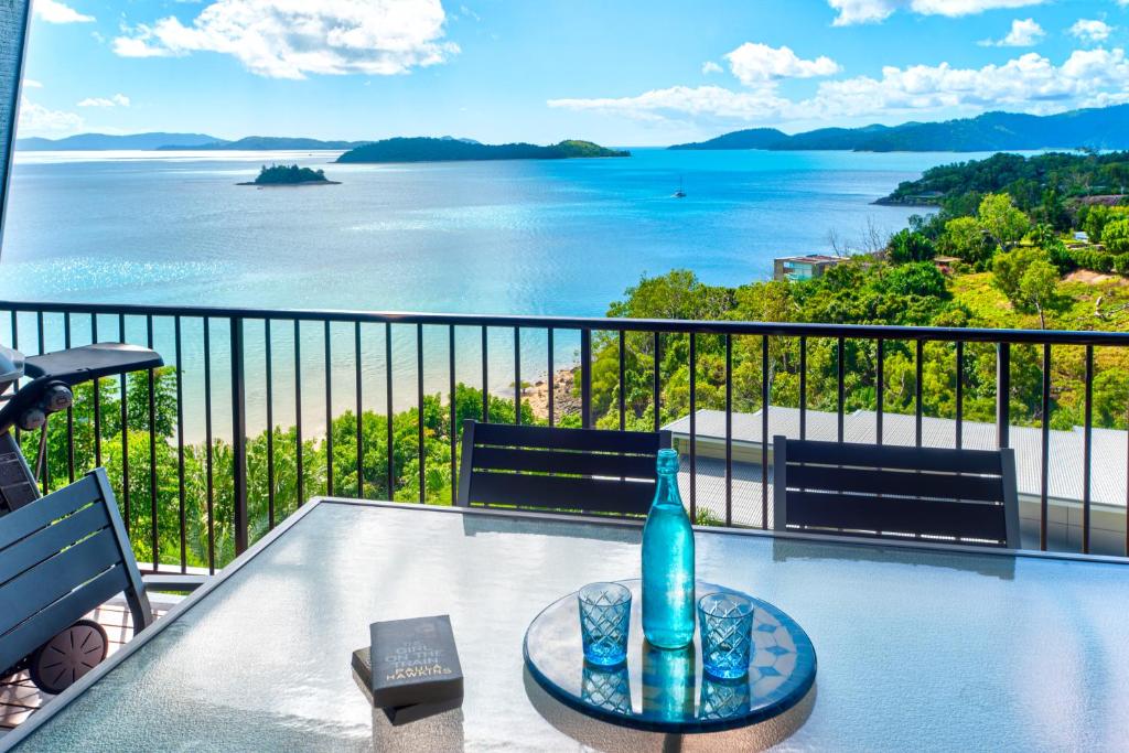 a view of the water from a balcony with a bottle on a table at The Panorama 3, Hamilton Island 2 Bedroom 2 Bathroom Ocean View Modern Apartment in Hamilton Island