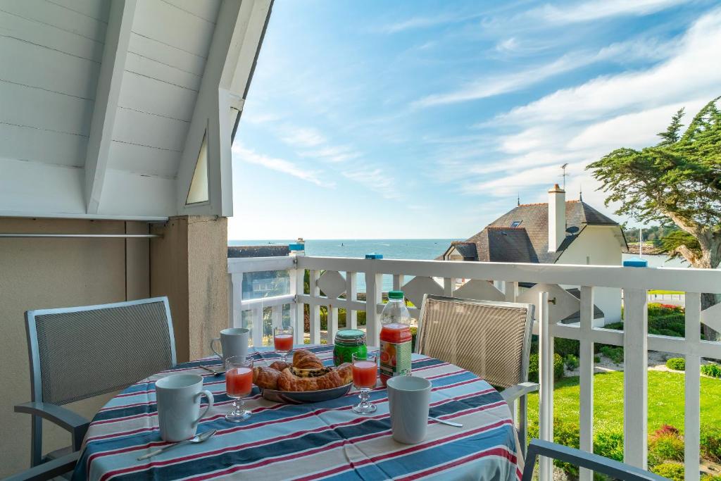 a table on a balcony with a view of the ocean at Plein Sud - Piscine partagée in Bénodet