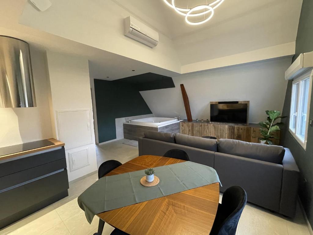 uma sala de estar com um sofá e uma mesa em Gite Spa L'Atelier Emile - Spa Privatif - 5 min COLMAR em Sainte-Croix-en-Plaine