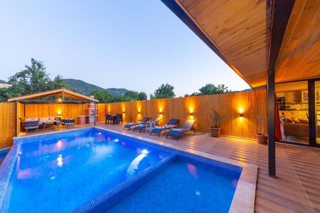 a swimming pool in a backyard with a wooden deck at Villa Nostalji Kalkan Bezirganda Havuzlu Villa in Bezirgân