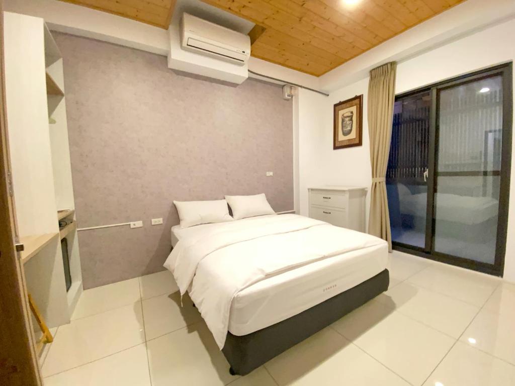 een slaapkamer met een wit bed en airconditioning bij 108 House Inn in Tainan