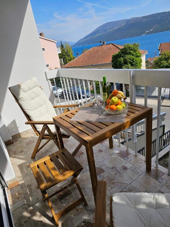 a wooden table with a bowl of fruit on a balcony at Apartment Mimi in Herceg-Novi