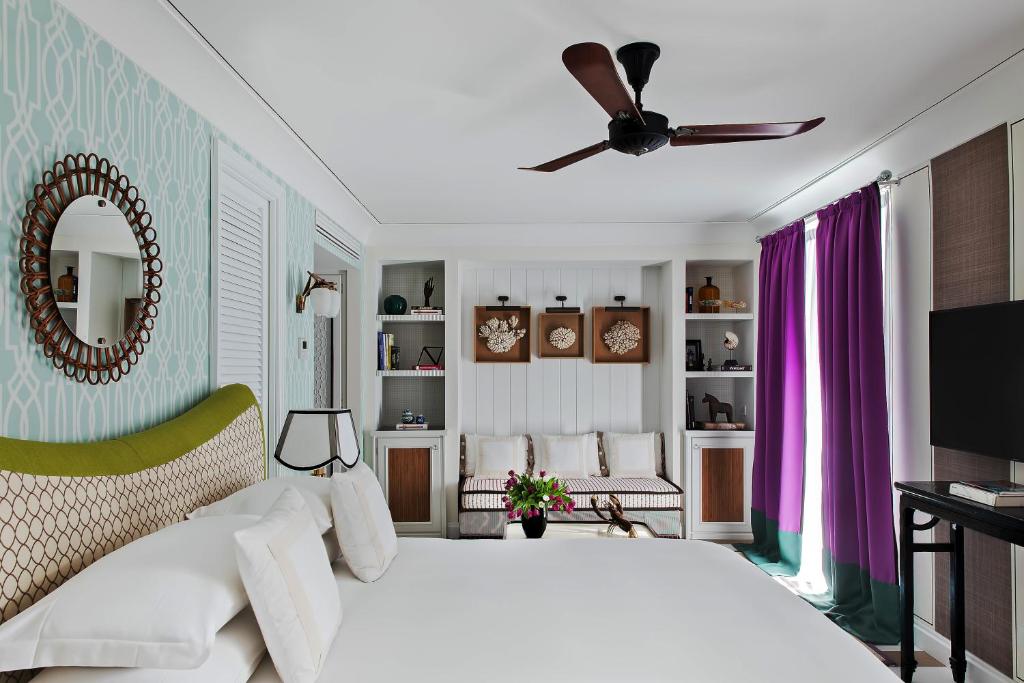 a bedroom with a white bed and a ceiling fan at Capri Tiberio Palace - The Leading Hotels of the World in Capri