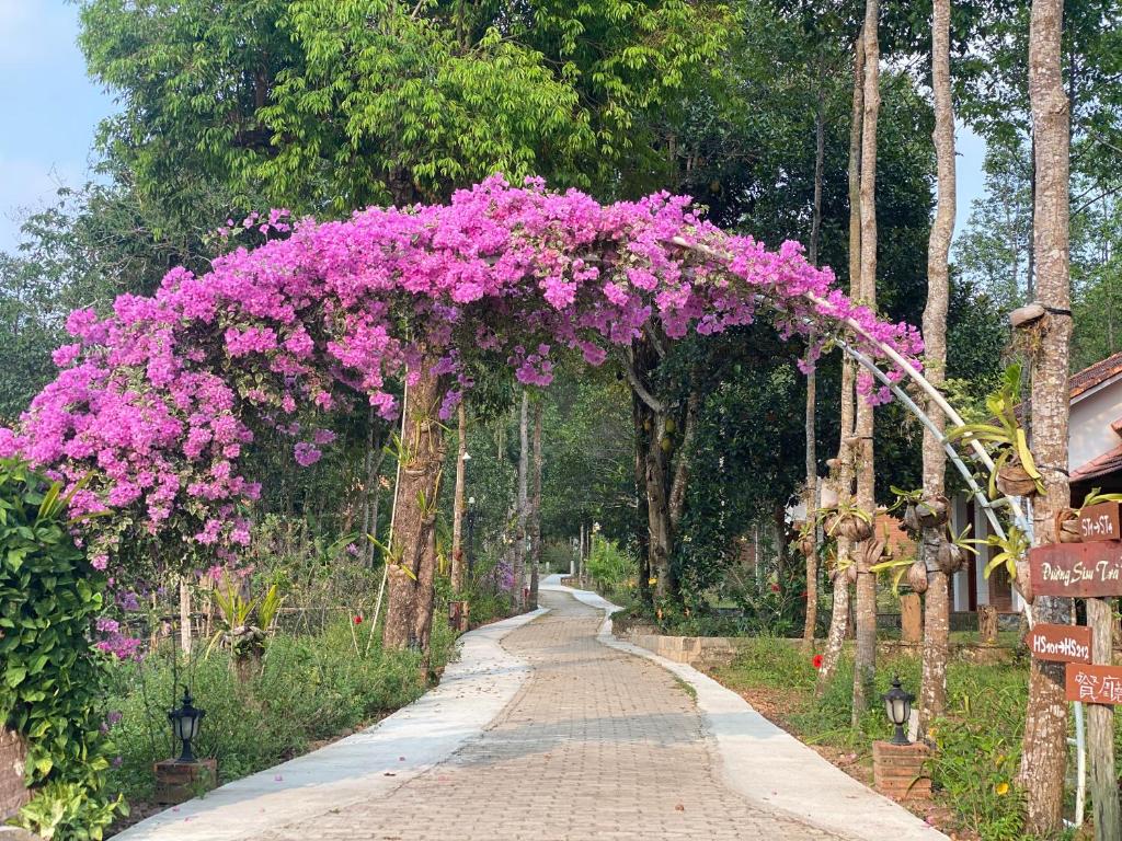 an arch covered in pink flowers on a road at The Garden House Phu Quoc Resort in Phu Quoc