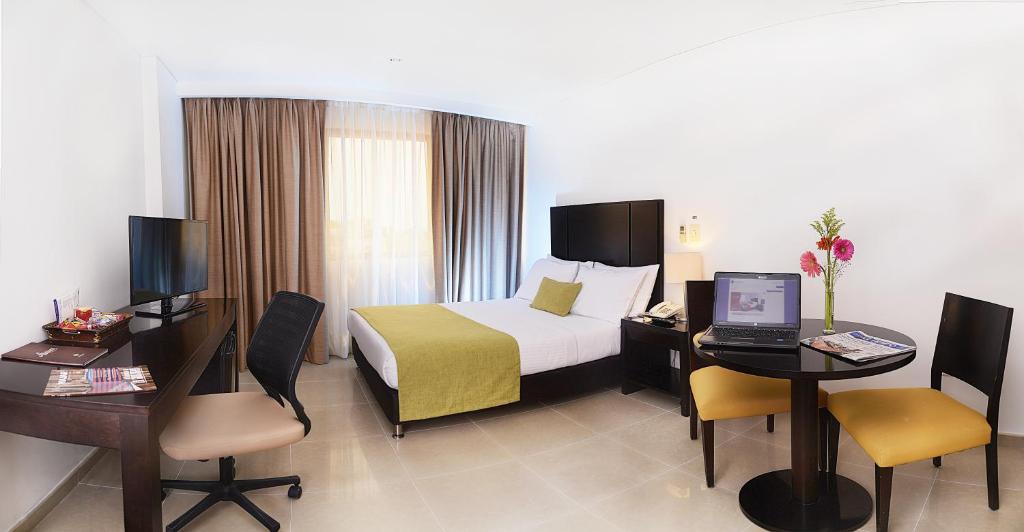 a hotel room with a bed and a desk with a laptop at Hotel Millenium Barrancabermeja in Barrancabermeja