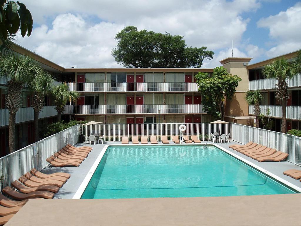 uma piscina em frente a um hotel com cadeiras em Red Carpet Inn Airport Fort Lauderdale em Fort Lauderdale