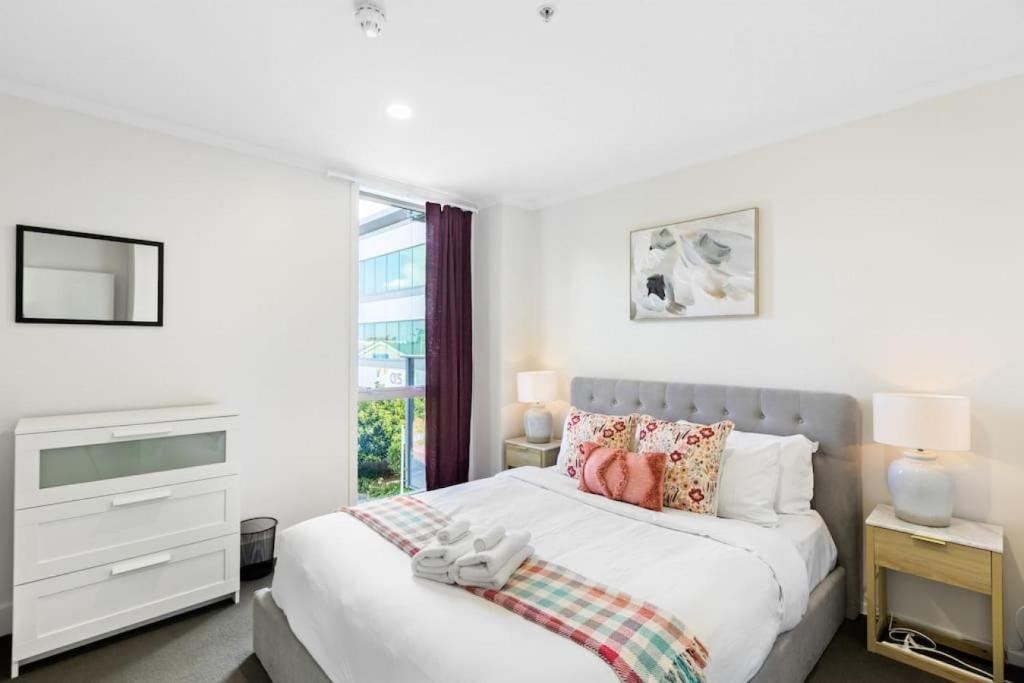 a white bedroom with a bed and a window at Superb 2BR Aprt in Central City - Wifi - Netflix in Auckland