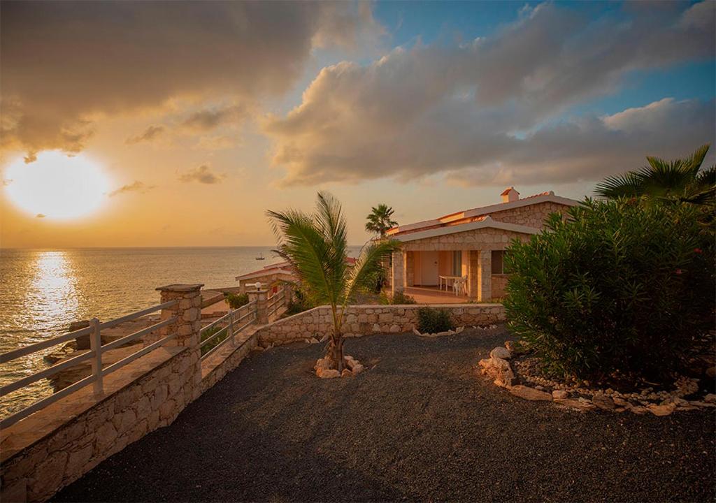 a house on the beach with the sunset in the background at Villa Lagosta Stella Maris Exclusive in Vila do Maio