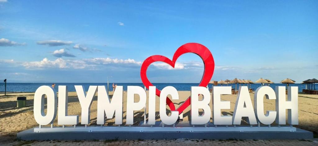 een bord op het strand met een rood hart bij Indigo luxury apartments in Olympiakí Aktí