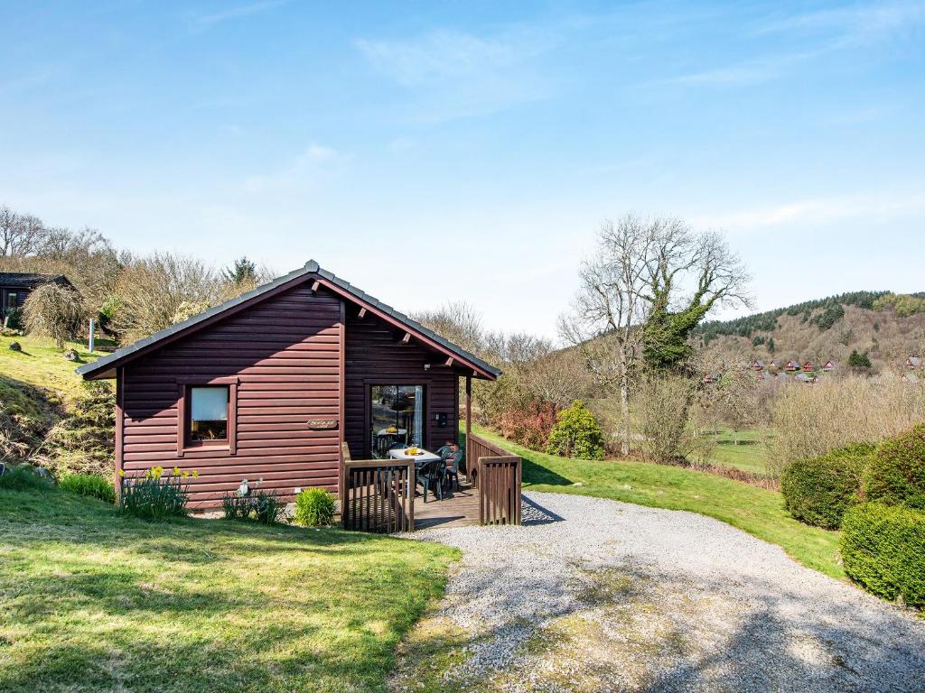 a small cabin with a porch on a grass field at Bengairn in Fairgirth