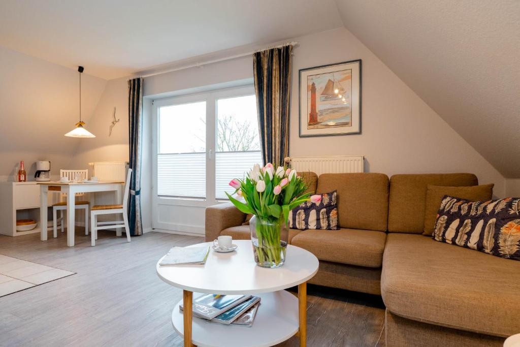 a living room with a couch and a table with flowers at Ferienwohnung Seeute Deern in Westerland