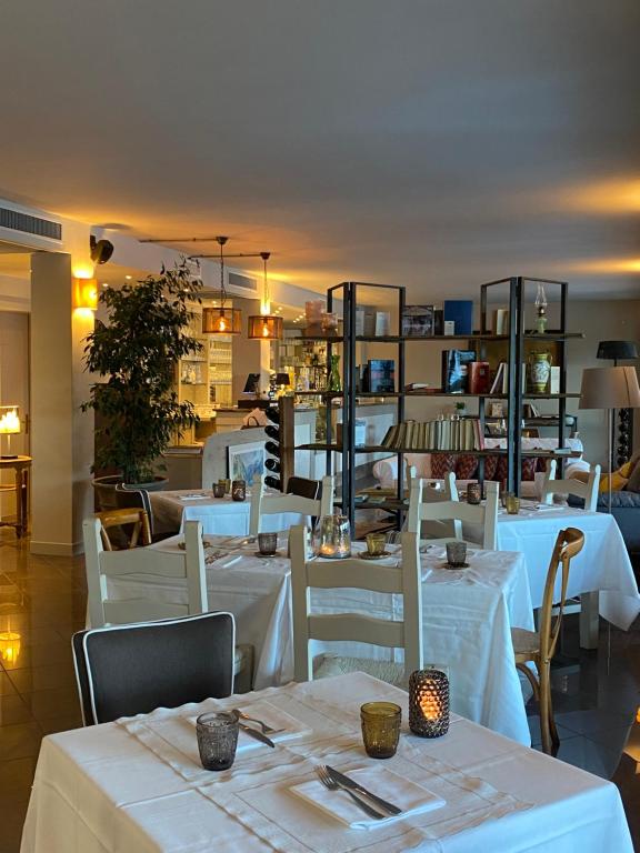 un ristorante con tavoli bianchi e sedie bianche di Residence Dalco Suites & Apartments a Limone sul Garda