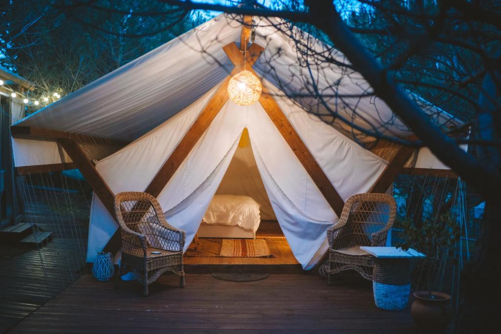 a tent with two chairs and a bed in it at Kabaceira Glamping in Atalaia