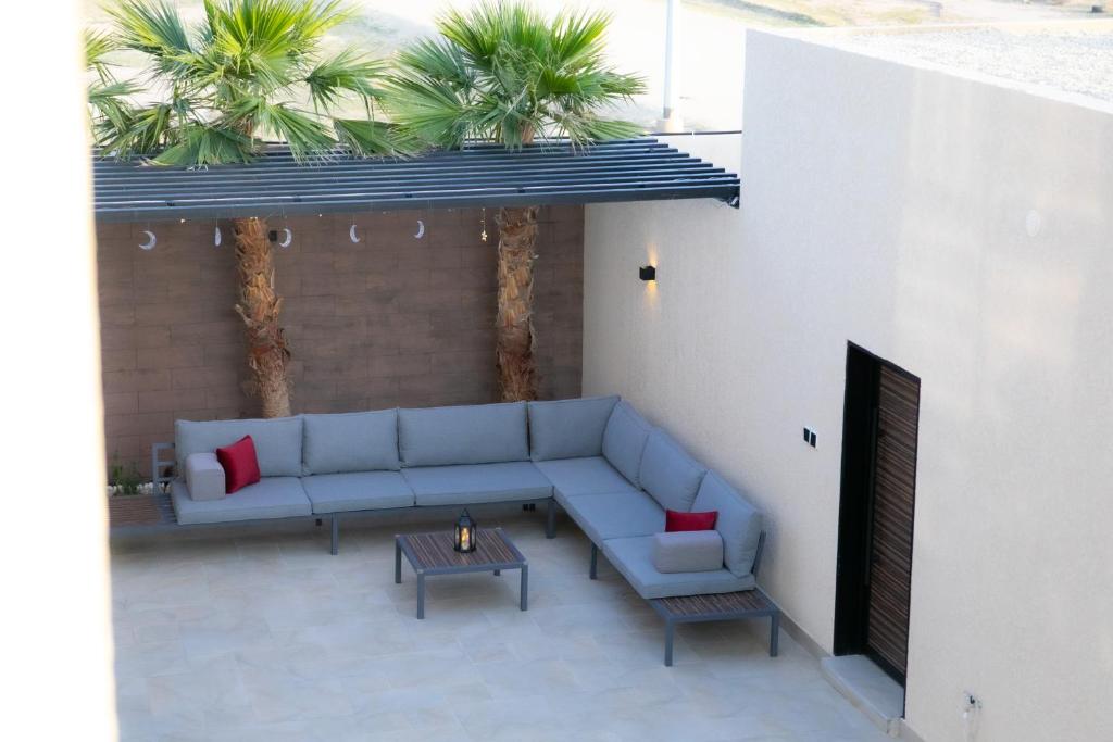 un patio con sofá, mesa y palmeras en بيرفيلا, en Al Rass