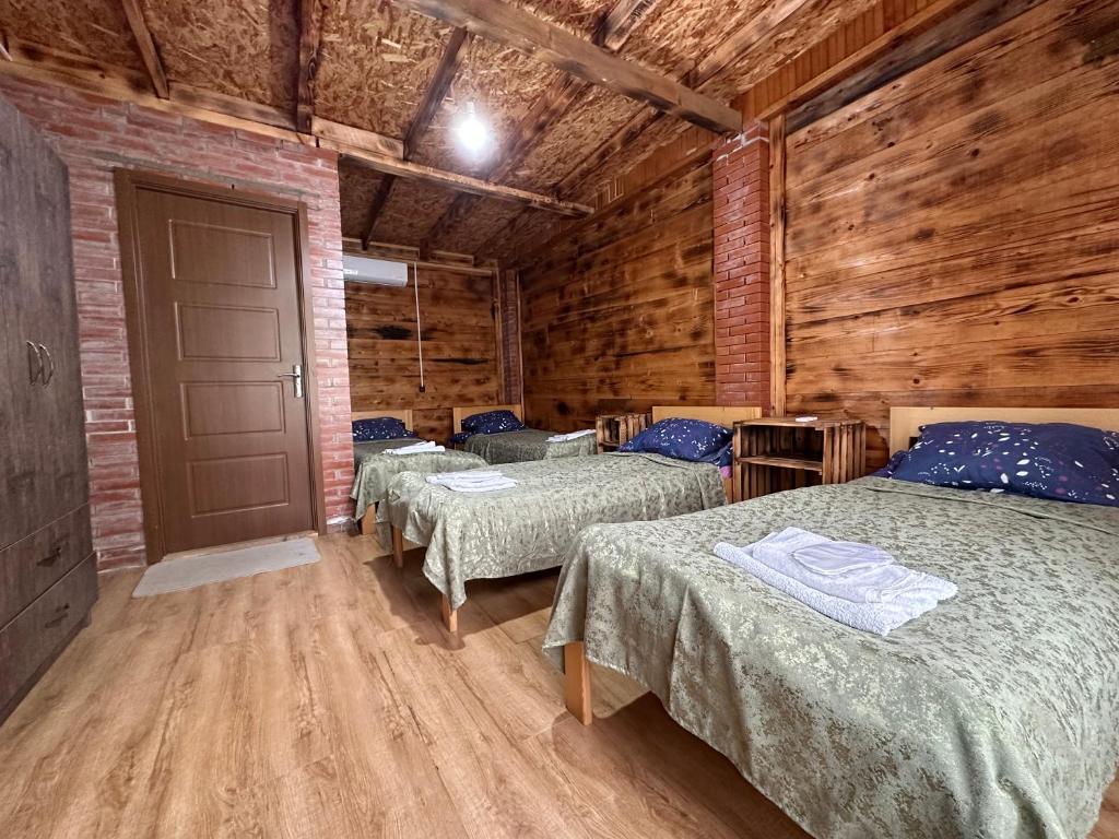 two beds in a room with wooden walls at Martvili canyon cottage in Gachedili