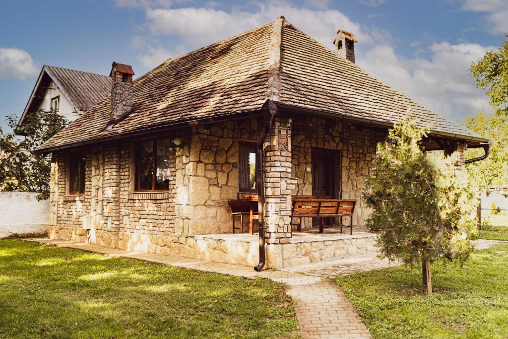 una vecchia casa in pietra con una panchina nel cortile di ENIGMA a Vrdnik