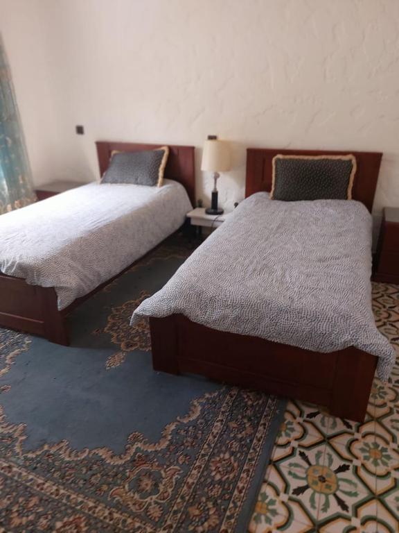 a bedroom with two beds and a rug at Villa kaoutar in Martil