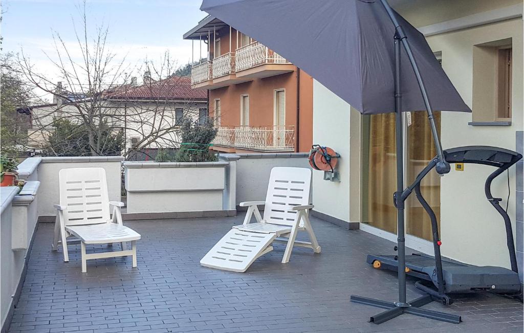 due sedie bianche e un ombrellone su un patio di Nice Apartment In Petrignano Bivio With Kitchen a Casette