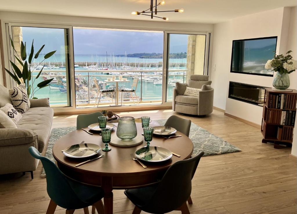 a living room with a table and chairs with a view of a harbor at Appt Vue Mer Exceptionnelle Triple Expo - 70m 2ch - Rénové in Saint-Cast-le-Guildo