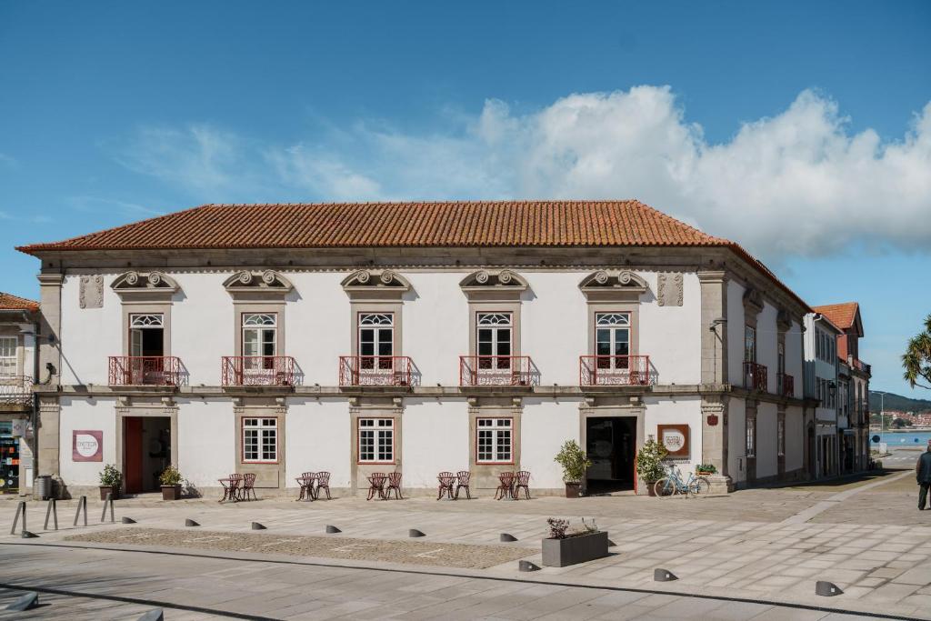 a large white building with a terrace on a street at Design & Wine Hotel in Caminha