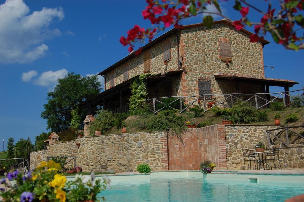 - un bâtiment au sommet d'un mur en pierre avec une piscine dans l'établissement Le Terre Di Giano, à Paciano