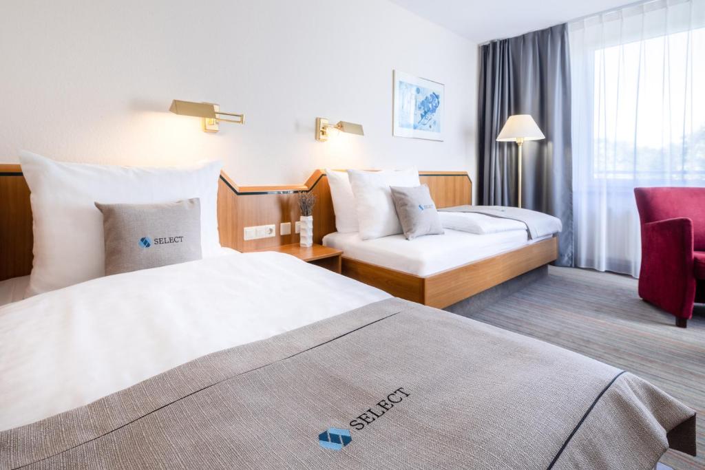 Select Hotel Solingen في سولينغين: غرفة فندقية بسريرين وكرسي