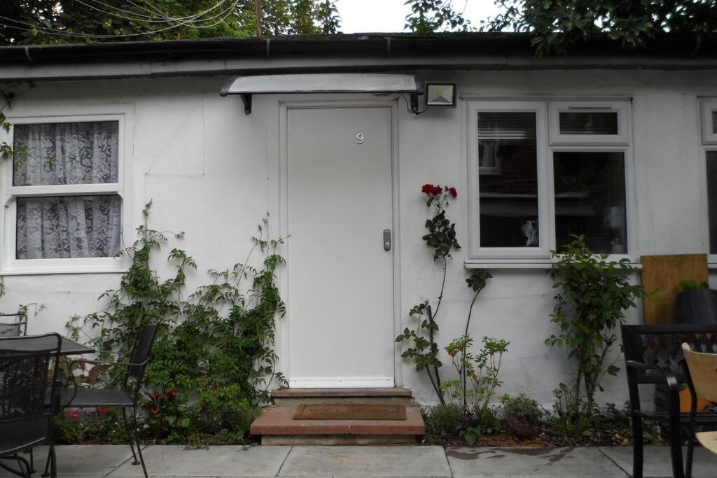 ein weißes Haus mit einer weißen Tür und zwei Fenstern in der Unterkunft Bubblesbnb, 1 bedroom flat in London