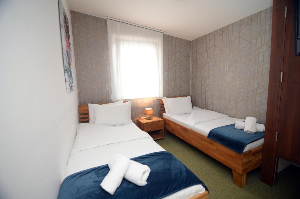 um pequeno quarto com 2 camas e uma janela em Apartmani Čarolija em Lučani