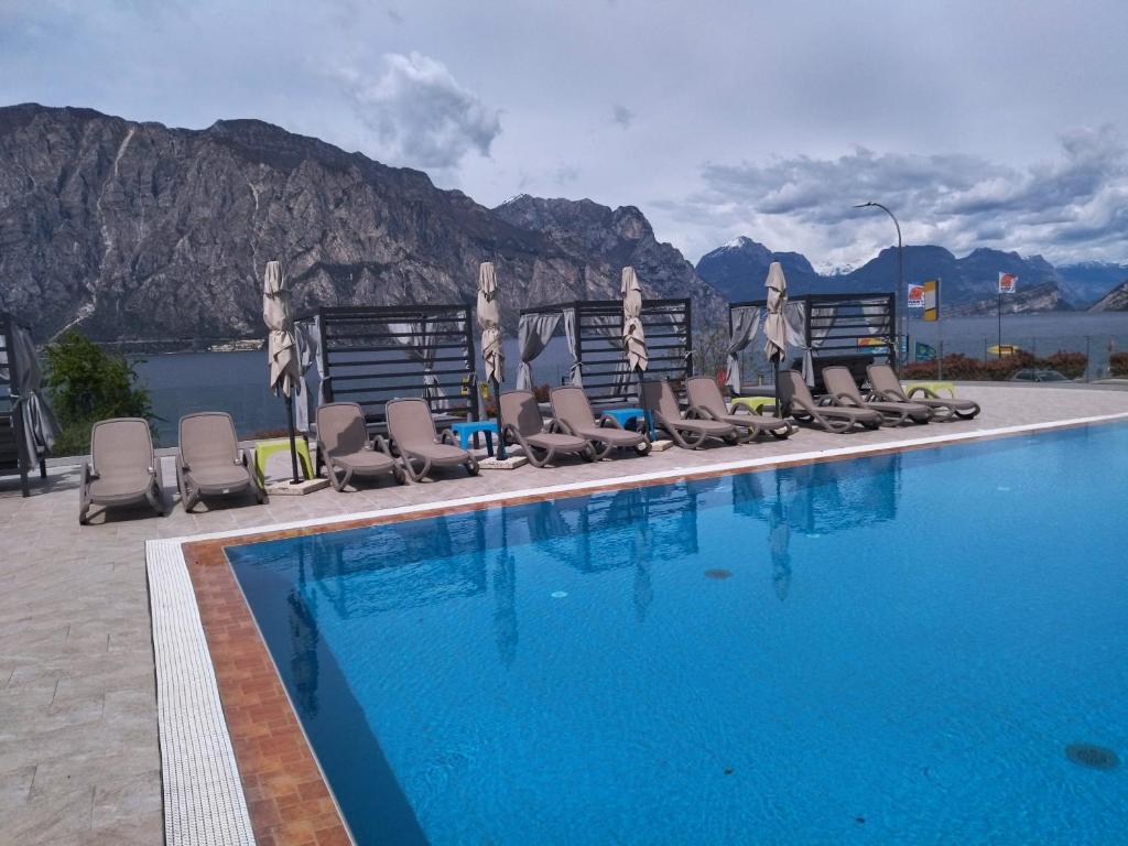 a swimming pool with chaise lounge chairs next to a mountain at Hotel Sole Malcesine in Malcesine