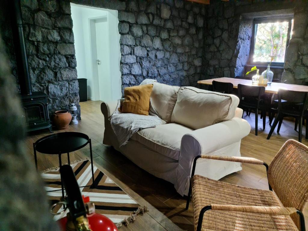 ein Wohnzimmer mit einem Sofa und einem Tisch in der Unterkunft Quinta do Caminho da Igreja TER-Casas de Campo in Velas