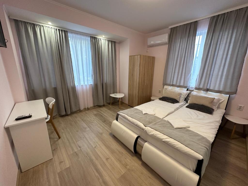 sypialnia z łóżkiem, biurkiem i oknami w obiekcie Utopia Apartment 1, by LMG w mieście Chisaria