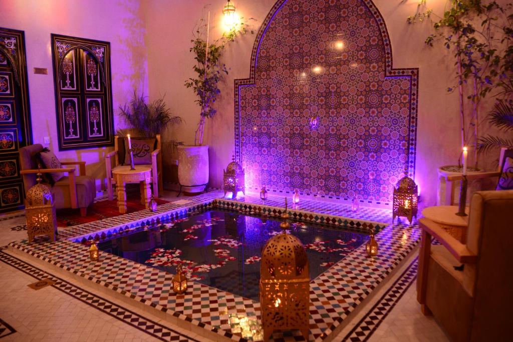 einen Pool in einem Haus mit lila Lichtern in der Unterkunft Riad Bab Nour in Marrakesch