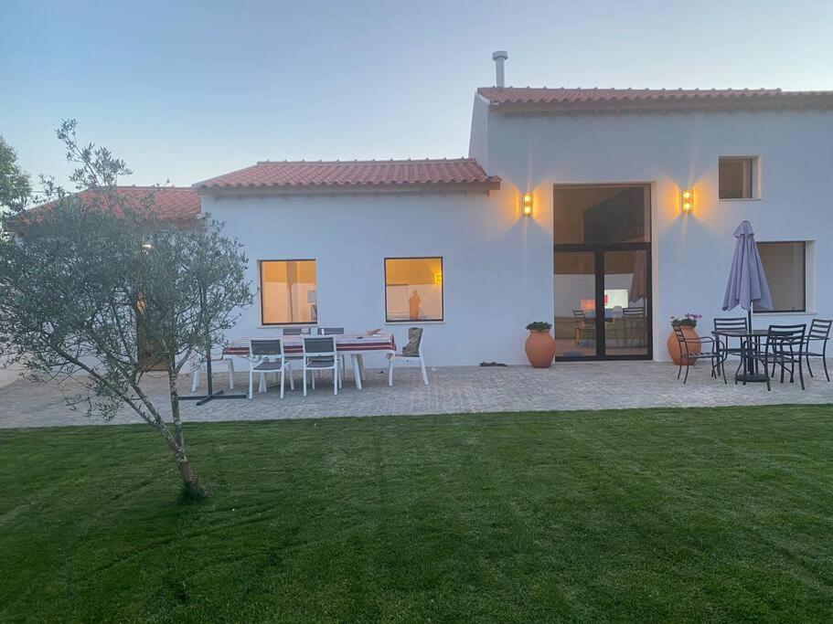 a white house with tables and chairs in a yard at Casa do Carvalhal - Quinta do Soldado in Alquerubim