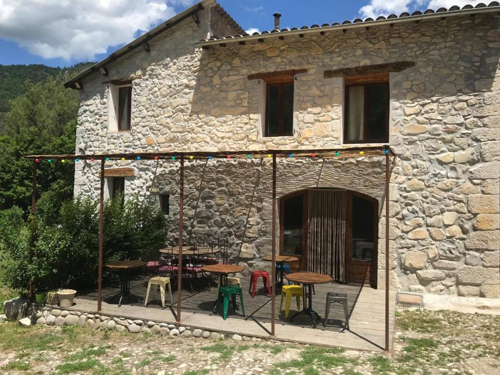 ein Steinhaus mit einer Terrasse mit Tischen und Stühlen in der Unterkunft Gîte d'étape Bastide Petra Castellana Verdon in Castellane