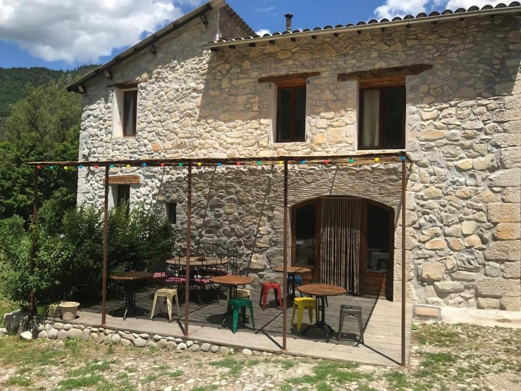 kamienny dom z tarasem ze stołami i krzesłami w obiekcie Gîte d'étape Bastide Petra Castellana Verdon w mieście Castellane