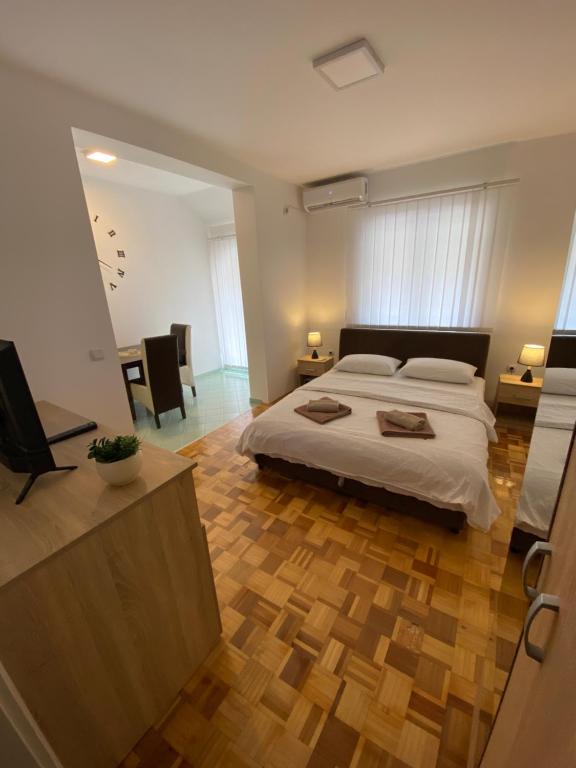 um quarto com uma cama grande e piso em madeira em Apartmani Milojić em Sokobanja