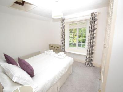 a white bedroom with a bed and a window at Quince Cottage in Ventnor