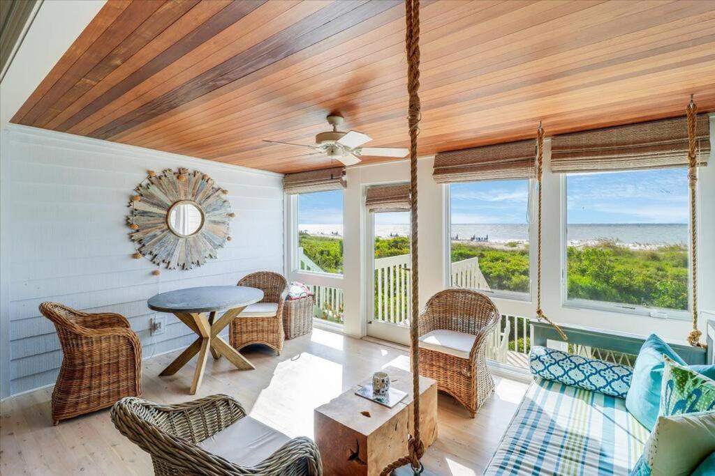 a living room with a table and chairs and windows at Beach Club Villa 30 - Coastal Oceanfront! Pool! Walkout! in Isle of Palms