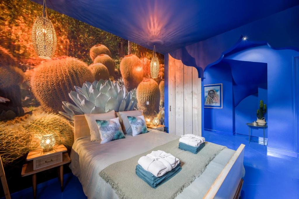 a blue bedroom with a bed with towels on it at Luxury Jardin Majorelle paris orly avec jacuzzi in Vigneux-sur-Seine