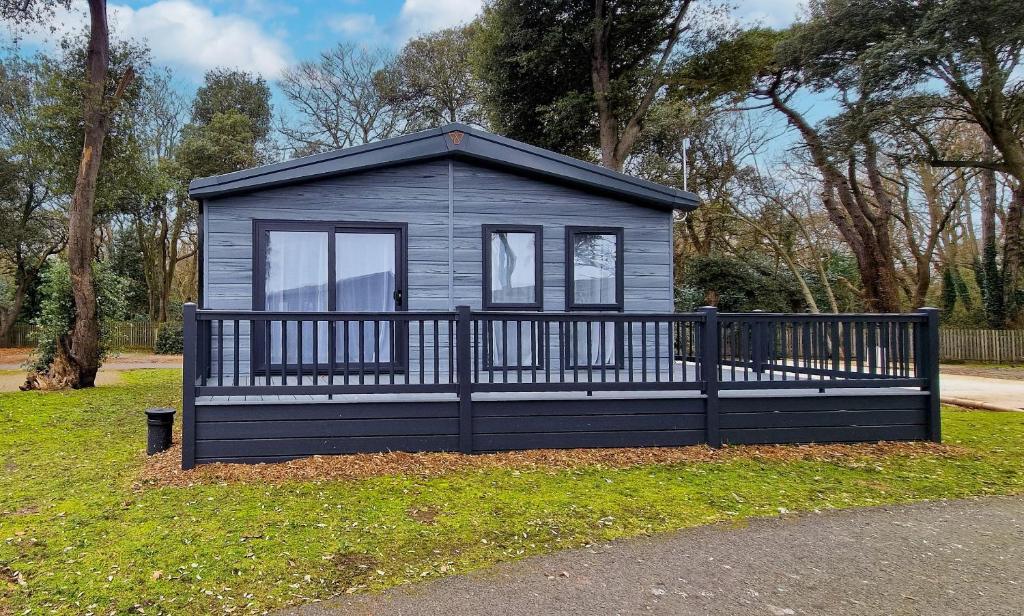 a small house with a fence in the grass at Stunning Lodge With Large Decking At Azure Seas In Suffolk Ref 32109og in Lowestoft