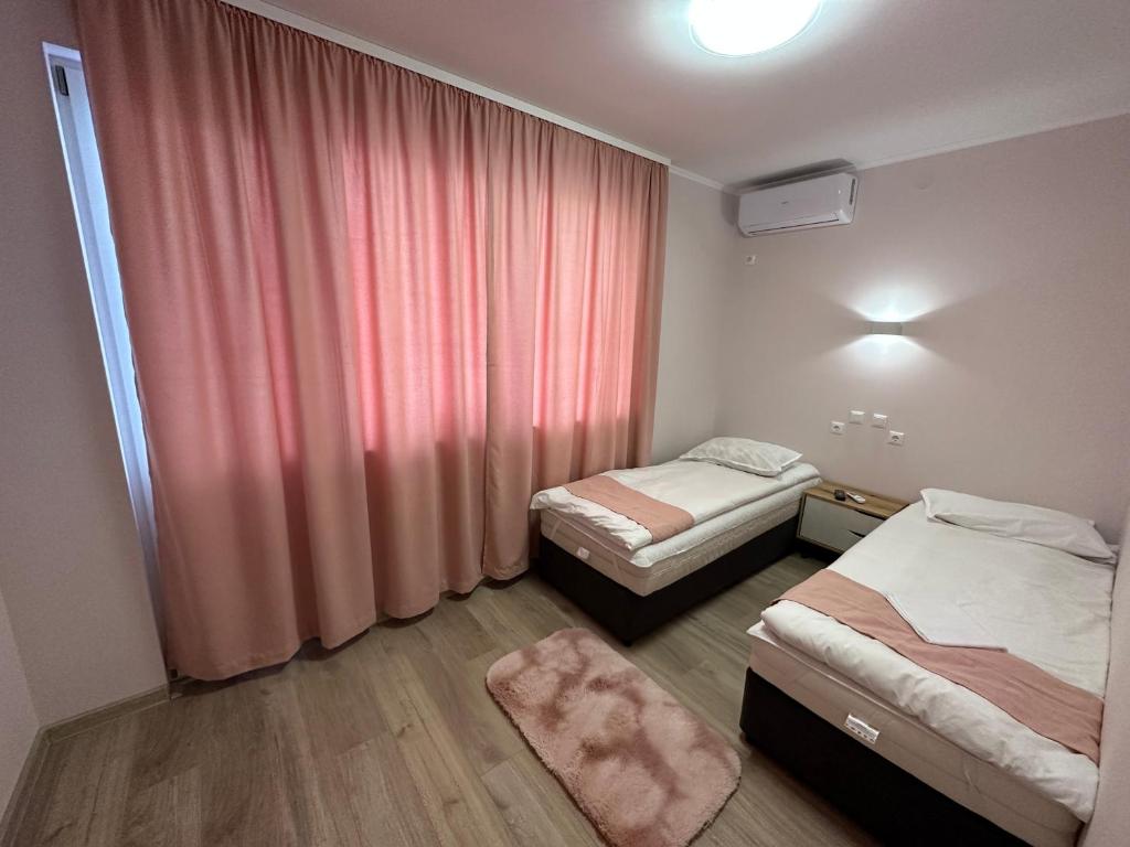 una camera d'albergo con due letti e una finestra di Utopia Apartment 3, by LMG a Hisarya